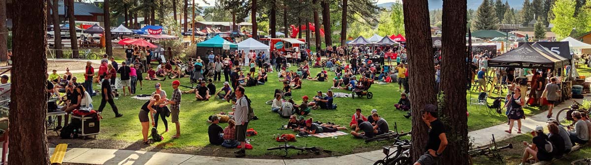 Crowd sitting on grass in a park with a festival atmosphere